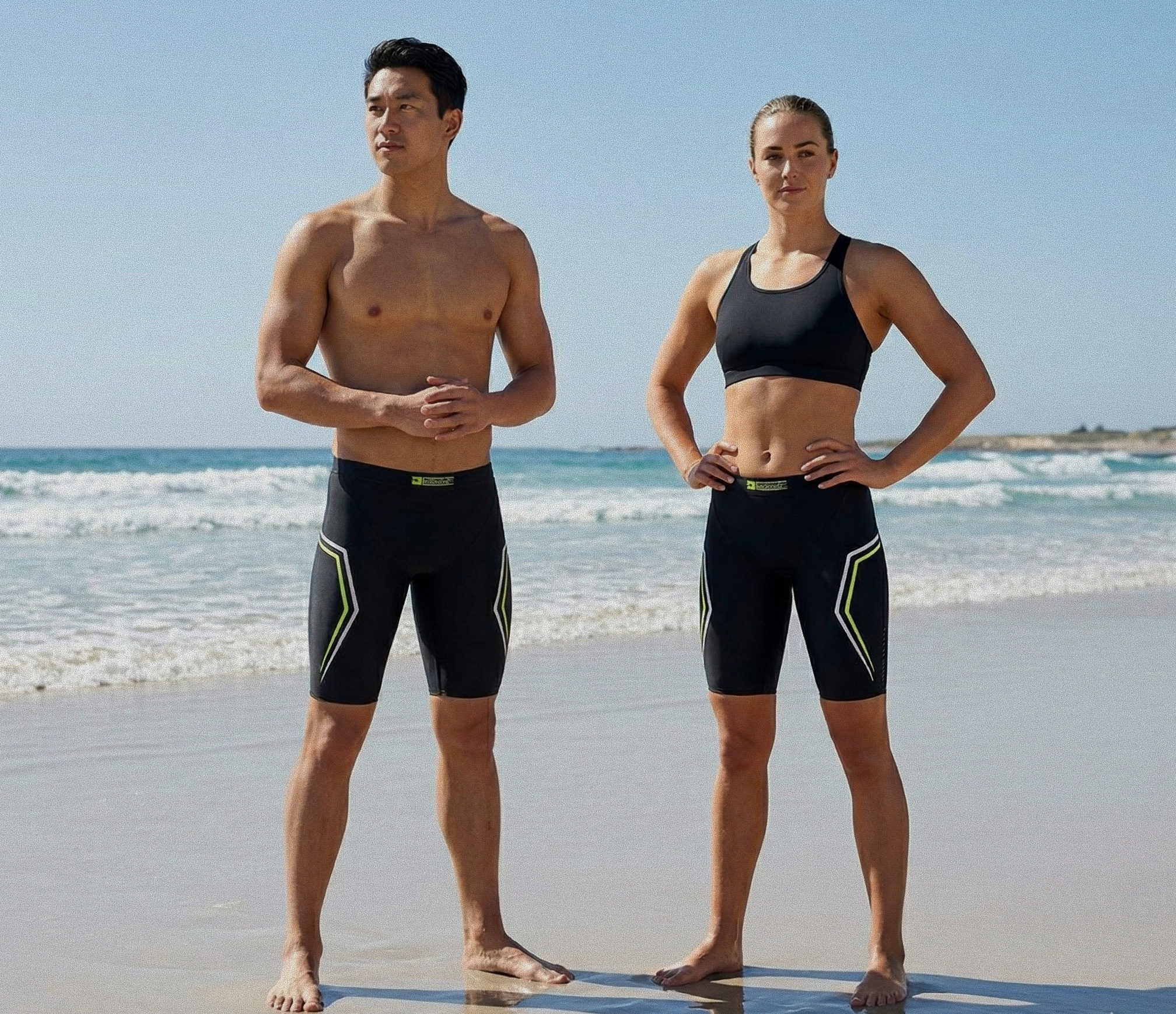 Male and female athletes wearing Zero Gravity Buoyancy Shorts with yellow accents on the beach, designed for triathlon training, swimming, and active performance, featuring a sleek, flexible, and high-performance fit.