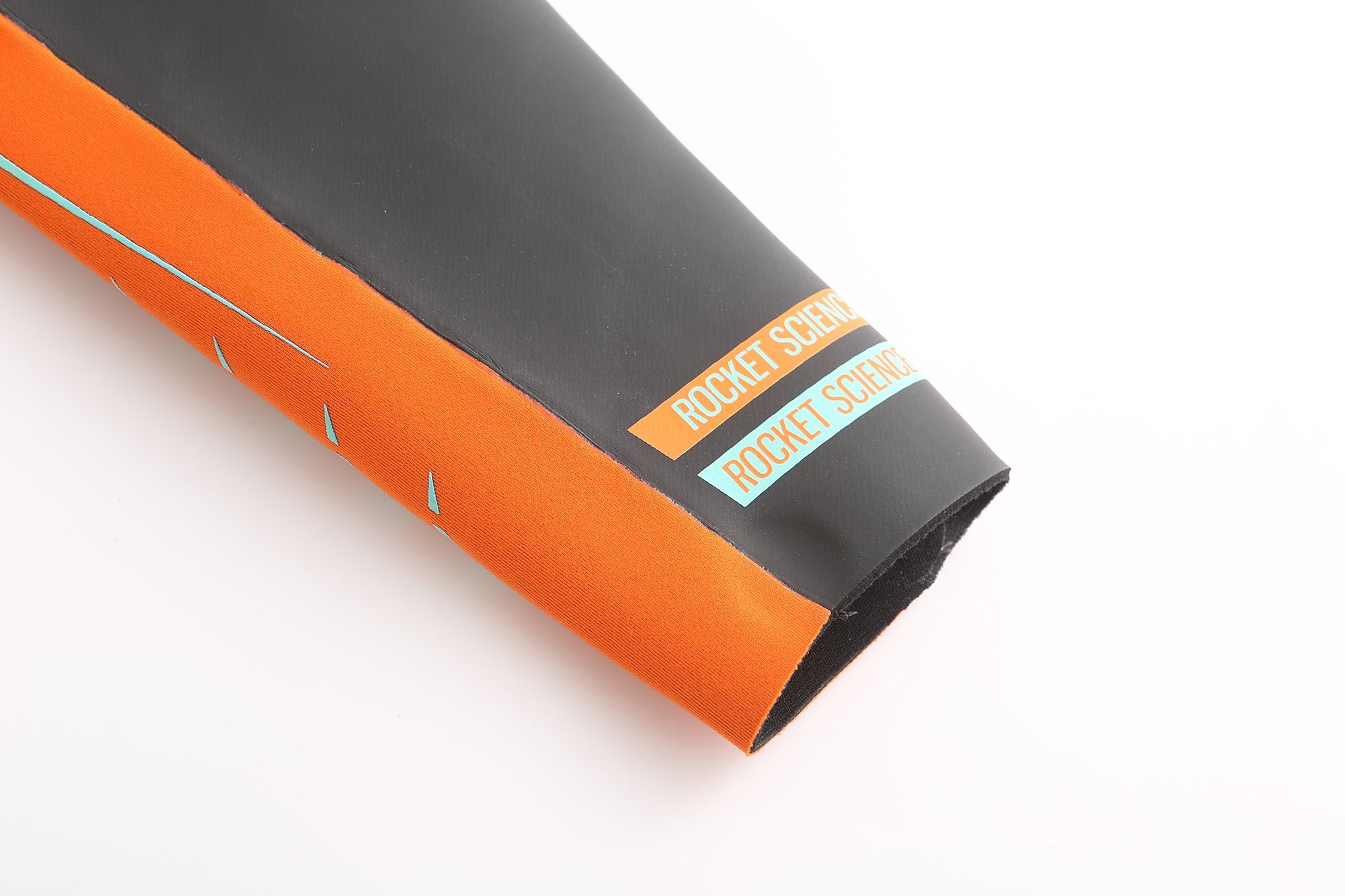 Close-up of Real J&J wetsuit sleeve with orange forearm panel and Rocket Science logo on black neoprene.