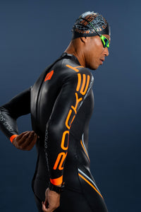 Side rear view of athlete wearing Rocket Science Sports Aquasense wetsuit, reaching for the reverse back zipper with orange sleeve branding visible