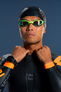 Front close-up of male athlete wearing Rocket Science Sports Viper wetsuit, adjusting collar, showing Ultra Flex chest panel and orange wrist cuffs