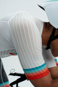 Close-up of a person wearing a white cycling outfit with colorful accents.