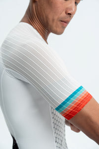 Person wearing a white athletic shirt with colorful arm band on a light gray background